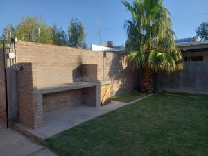 a brick wall with a bench next to a palm tree at Departamento céntrico San Rafael in San Rafael