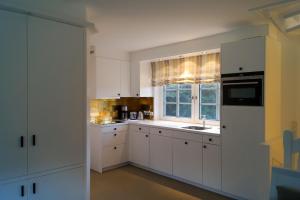 a white kitchen with white cabinets and a window at Hüs Claire in Kampen