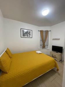 a bedroom with a yellow bed and a television at SUITE Dreams CARROLL 11 in Paterson
