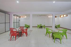 a room with green and red chairs and tables at OYO Omi Guest House in Gurgaon