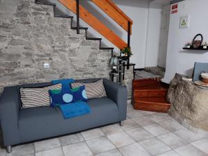 Recanto da Pedra في لينهاريس: أريكة زرقاء في غرفة معيشة مع جدار حجري