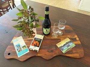 a wooden table with a bottle of wine and wine glasses at The Old School House in Emu Bay