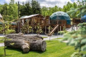 a playground with a large log in the grass at Glamping TOMAMU in Tomamu