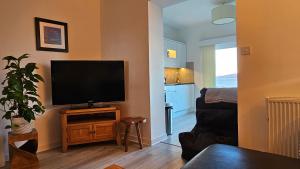 sala de estar con TV de pantalla plana en la pared en Ards House Self catering apartment with sea views, en Oban