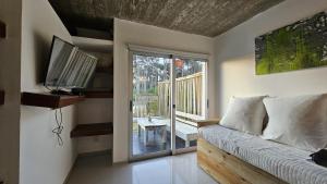 1 dormitorio con 1 cama y balcón con TV en Apart Hotel El Caracol, en José Ignacio