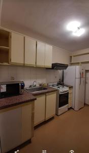 a kitchen with white cabinets and a stove and refrigerator at Apart Decorama in Dolores