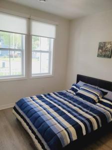 um quarto com uma cama azul e branca e 2 janelas em Adorable Cottage Port Stanley em Port Stanley