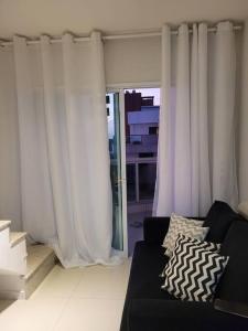 uma sala de estar com cortinas brancas e um sofá em Apartamento Duplex (Cobertura) Praia do Forte em Cabo Frio