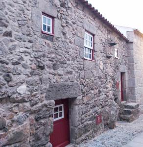 a stone building with a red door and two windows at Recanto da Pedra in Linhares