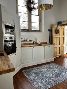 cocina con armarios blancos y alfombra en The Old School House Retreat, en Tibberton