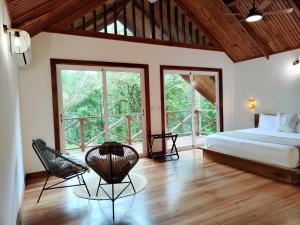 a bedroom with a bed and chairs in a room with windows at Gaia Nature Lodges at Bluff Beach in Bocas del Toro