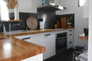cocina con armarios blancos y encimera de madera en Rudelle maison de vacances en Rudelle