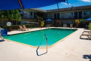 a swimming pool at a hotel with a blue umbrella at Motel 6-Lantana, FL in Lantana