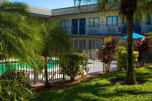 a fence in front of a building with palm trees at Motel 6-Lantana, FL in Lantana