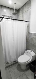 a bathroom with a toilet and a shower curtain at Vagón Resort in Cuatrociénegas de Carranza