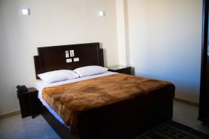 een slaapkamer met een groot bed met een houten hoofdeinde bij Sharks Bay Oasis Resort & Butterfly Diving Center in Sharm El Sheikh