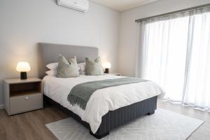 a white bedroom with a large bed with pillows at Atlantis Luxury Suites 3/4 in Swakopmund