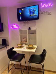 a table with two chairs and a tv on a wall at Honey Room22 , parking, proche gare in Saint-Brieuc