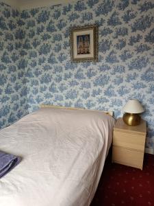 een slaapkamer met een bed met blauw bloemenbehang bij Lowry House Hotel in Great Barr in Birmingham