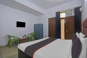 a bedroom with a bed and a desk and a television at OYO Omi Guest House in Gurgaon
