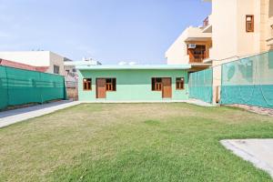 a house with a green facade and a yard at OYO Omi Guest House in Gurgaon