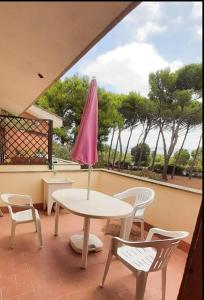 une table et des chaises sur un balcon avec un parasol rose dans l'établissement Casa Giannella, a due passi dal mare, à Giannella