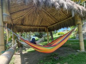 een persoon in een hangmat onder een rieten dak bij Casa de Orion in Ayangue