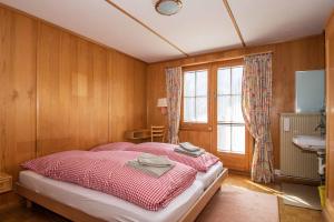 een slaapkamer met een bed, een wastafel en een raam bij Chalet Grimm in Adelboden