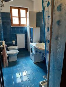 - une salle de bains carrelée de bleu avec 2 toilettes et un lavabo dans l'établissement Casa Giannella, a due passi dal mare, à Giannella