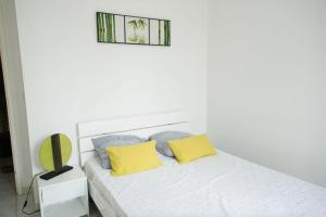 Dormitorio blanco con cama con almohadas amarillas en Beautiful 120m house, en Saint-Laurent-de-la-Salanque