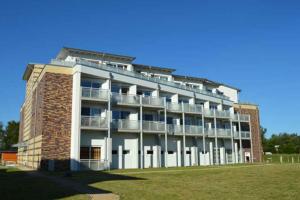 un gran edificio de ladrillo con balcones y un campo de césped en Käptn Brass Appartement 17 Ostseeperle, en Dierhagen