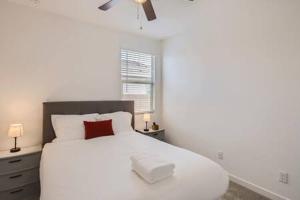 a white bedroom with a white bed with a red pillow at NEW - 5BR Home 20 min from Phoenix - AT in Avondale
