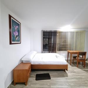 a bedroom with a bed and a table and a desk at Hotel San Marcos Las Lajas in Ipiales