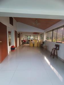 ein leeres Zimmer mit weißem Boden sowie Tischen und Stühlen in der Unterkunft Casa de Campo LA COBIJA in Calca