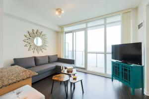 sala de estar con sofá y TV de pantalla plana en Skyline Elegance Condo en Toronto