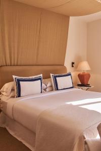 a bedroom with a large bed with blue and white pillows at Hotel Isabella's Llafranc in Llafranc