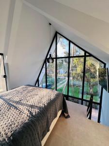 a bedroom with a bed and a large window at Cabana Sabá in Ibiúna