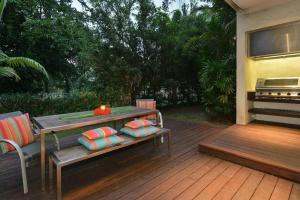 una terraza de madera con mesa y piano en 6 Beachfront Mirage - Luxury 4 Bedroom Home, en Port Douglas