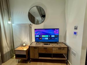 a television on a wooden stand in a room with a mirror at Tower Bridge London, 2 Bedrooms, Reception, Kitchen, Parking in London