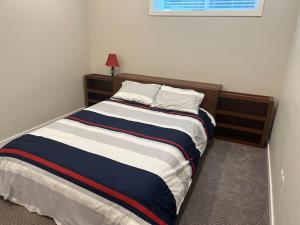 um quarto com uma cama com um cobertor azul e branco em Your Cozy Retreat, 2BR suite em Kamloops