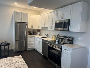 uma cozinha com armários brancos e um frigorífico de aço inoxidável em Your Cozy Retreat, 2BR suite em Kamloops