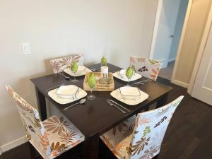 mesa de comedor con sillas y mesa negra con platos y vasos. en Your Cozy Retreat, 2BR suite en Kamloops