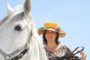 Une femme dans un chapeau debout à côté d'un cheval blanc dans l'établissement Les Maisons De Chante Oiseau, à Sigonce