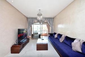 un soggiorno con divano blu e TV di Appartement Prestegia JAAD Near Aeroport a Marrakech