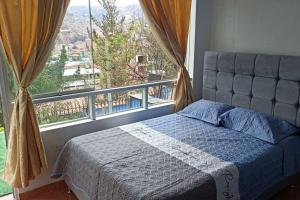 een slaapkamer met een bed en een groot raam bij Qori Garden Apartment in Cuzco