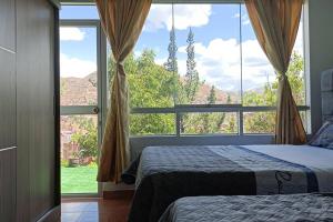 een slaapkamer met 2 bedden en een groot raam bij Qori Garden Apartment in Cuzco