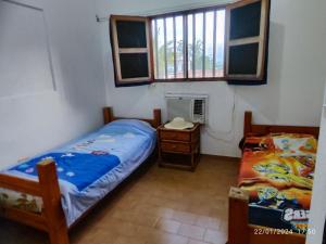 1 dormitorio con 2 camas, mesita de noche y ventana en Tú Casa de playa La Milagrosa en Boca de Uchire