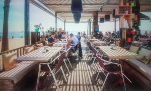 a restaurant with wooden tables and chairs and the beach at Gran apartamento ideal grupos muy cerca Barcelona in Badalona