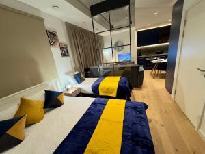 um quarto de hotel com duas camas com amarelo e azul em Amazing Cosy Apartment, Next to O2 Arena and close to London Excel, Secure Parking em Londres