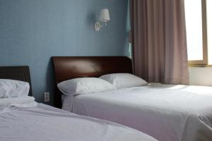 Duas camas sentadas uma ao lado da outra num quarto em Bexco Hostel B&B em Busan